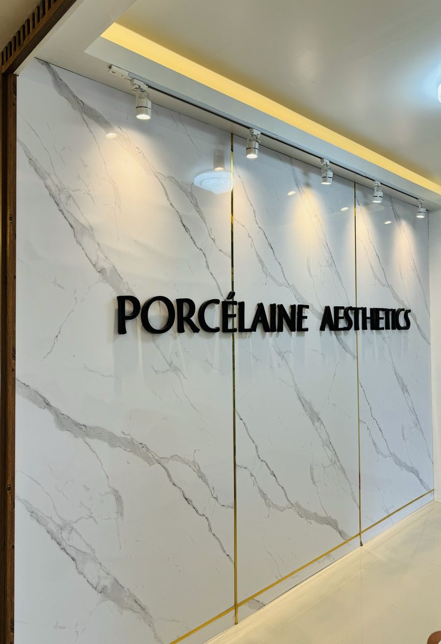 Marble feature wall with the Porcélaine Aesthetics name in black letters under track lights